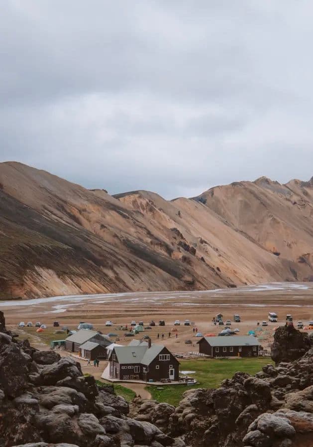 Landmannalaugar campsite — colorful tents in a wide valley below rhyolite-striped mountains